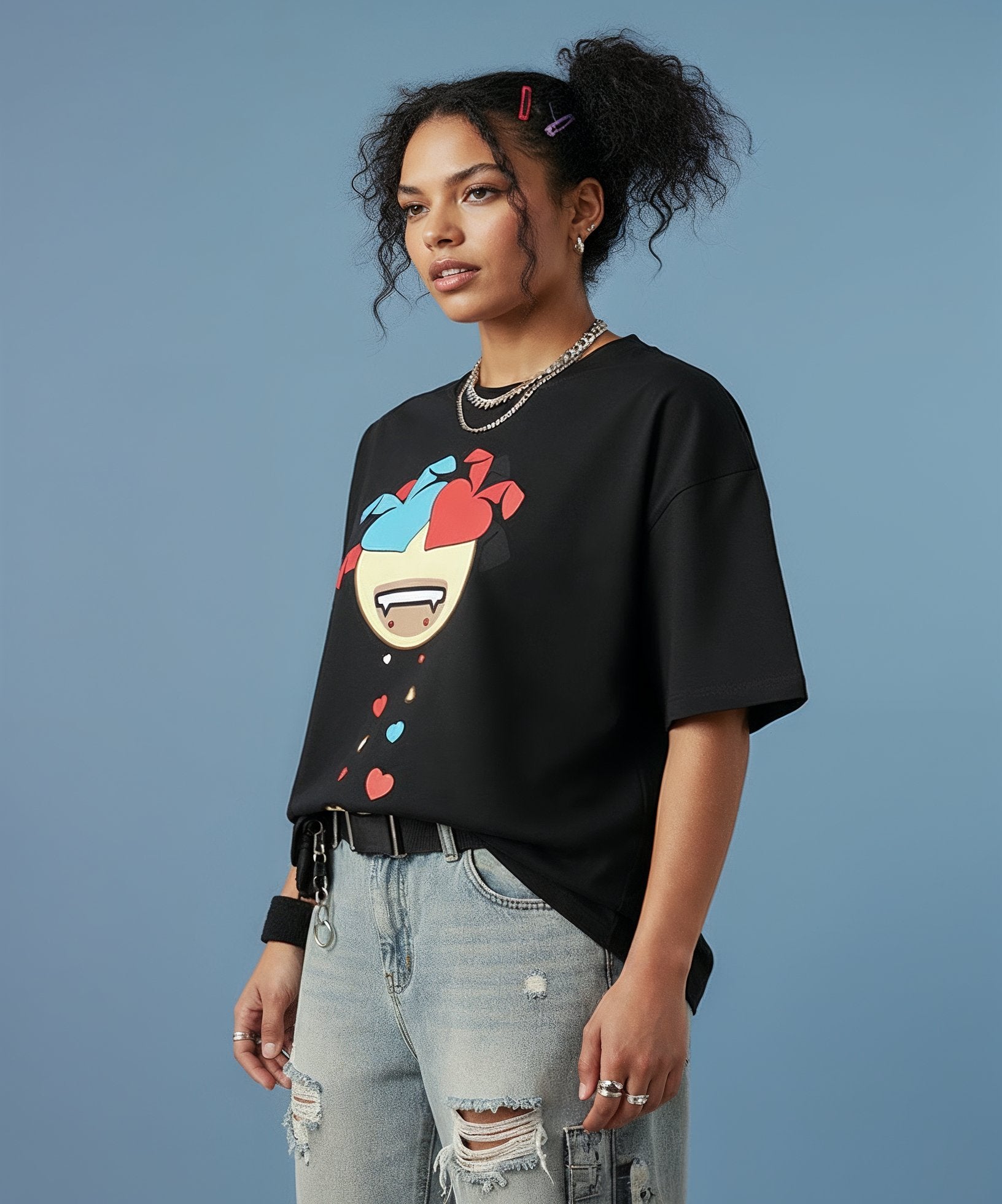 female wearing a black t-shirt with a colorful sweethearts emoji design on a blue background, side view