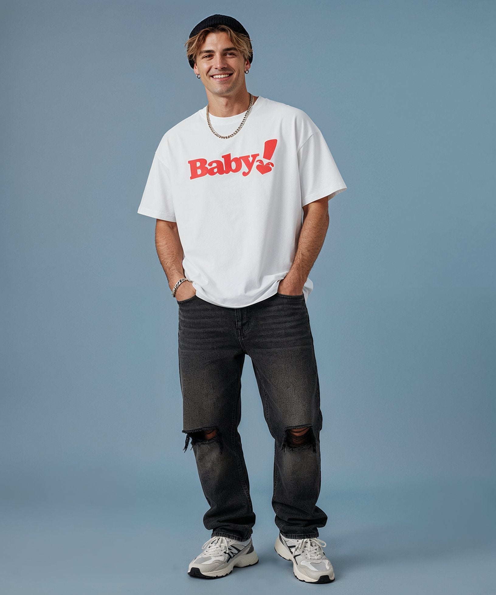 male wearing a white t-shirt with sweethearts "baby!" red text and black jeans on a blue background