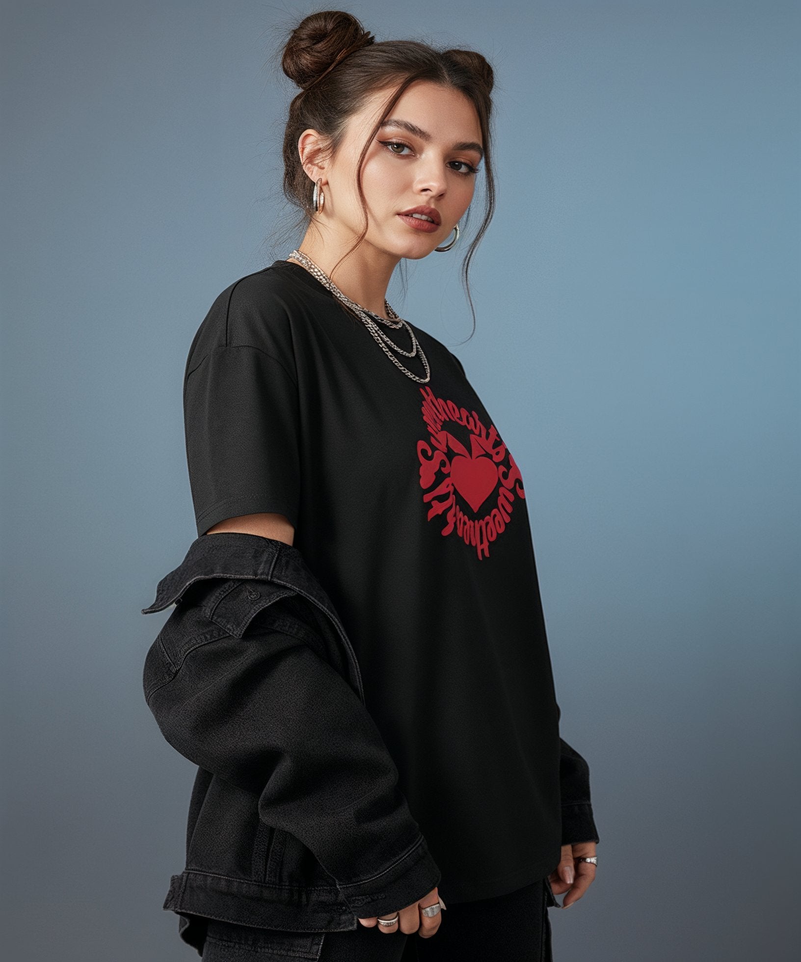 female wearing a black t-shirt with sweethearts red heart logo graphics and text in a circle and distressed jeans on a blue background, side view