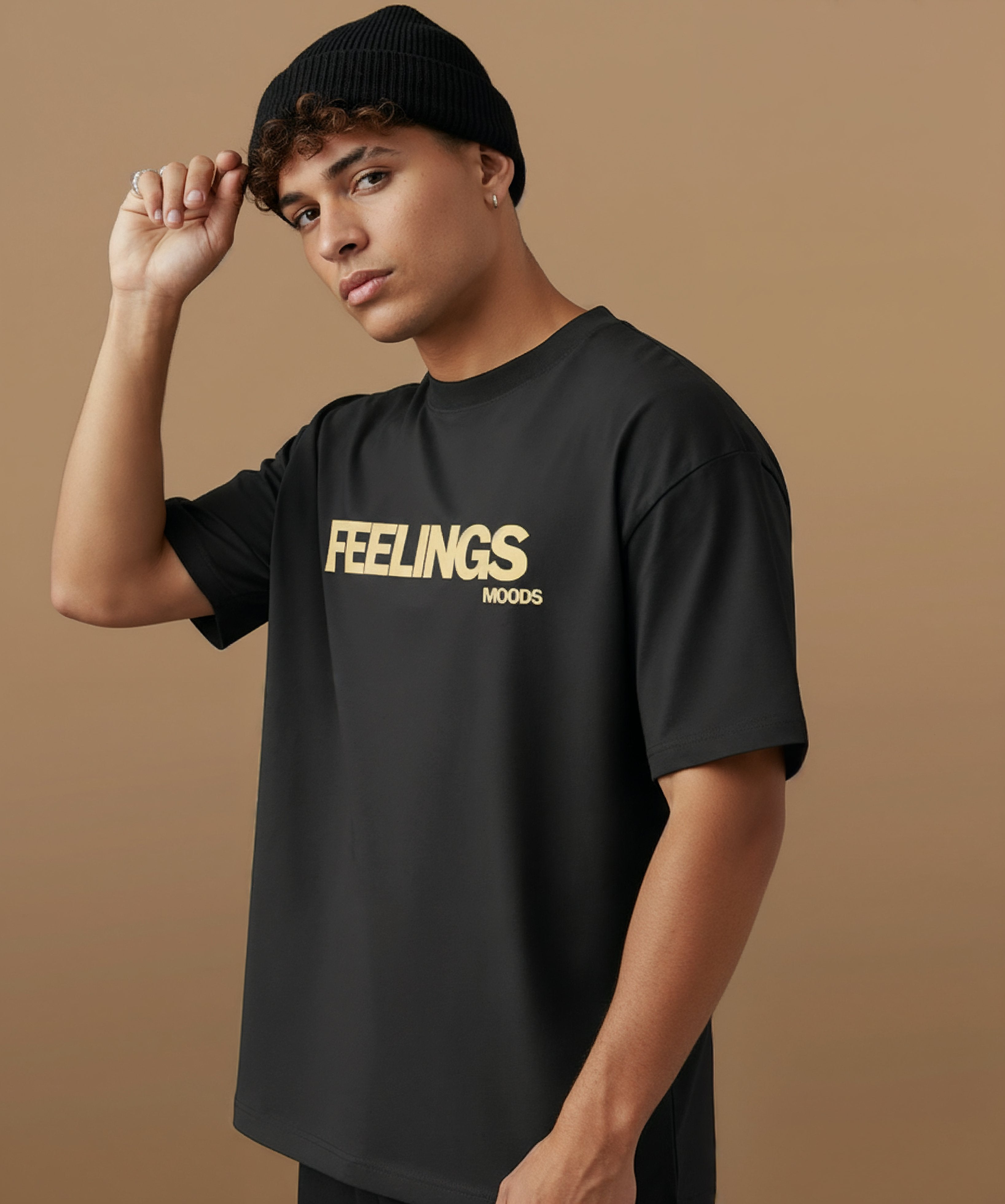 male model wearing a black t-shirt with  sweethearts brand 'FEELINGS MOODS' text on a brown background. angled left