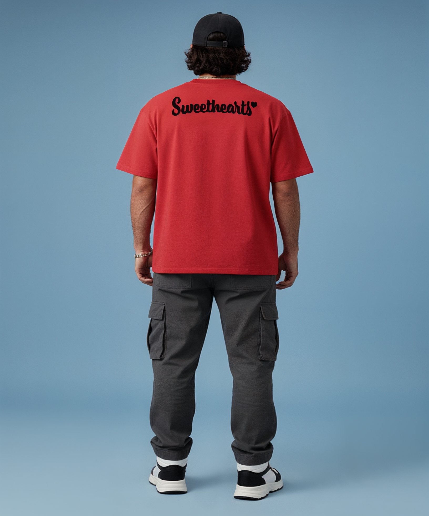 Person wearing a red t-shirt with 'Sweethearts' text on the back, standing against a blue background.