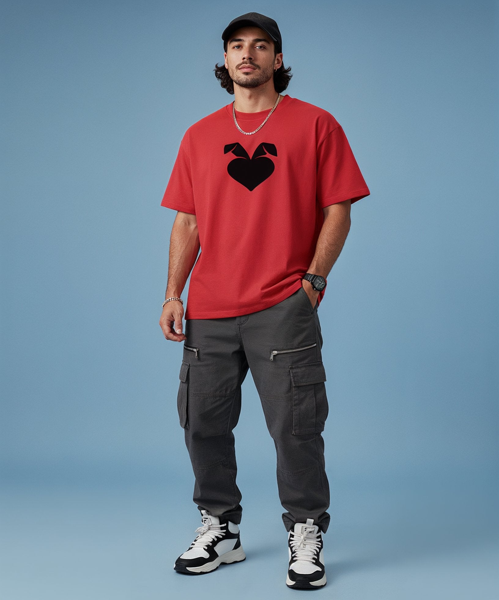 Man wearing a red t-shirt with a black sweethearts heart logo, gray cargo pants, and black and white sneakers on a blue background