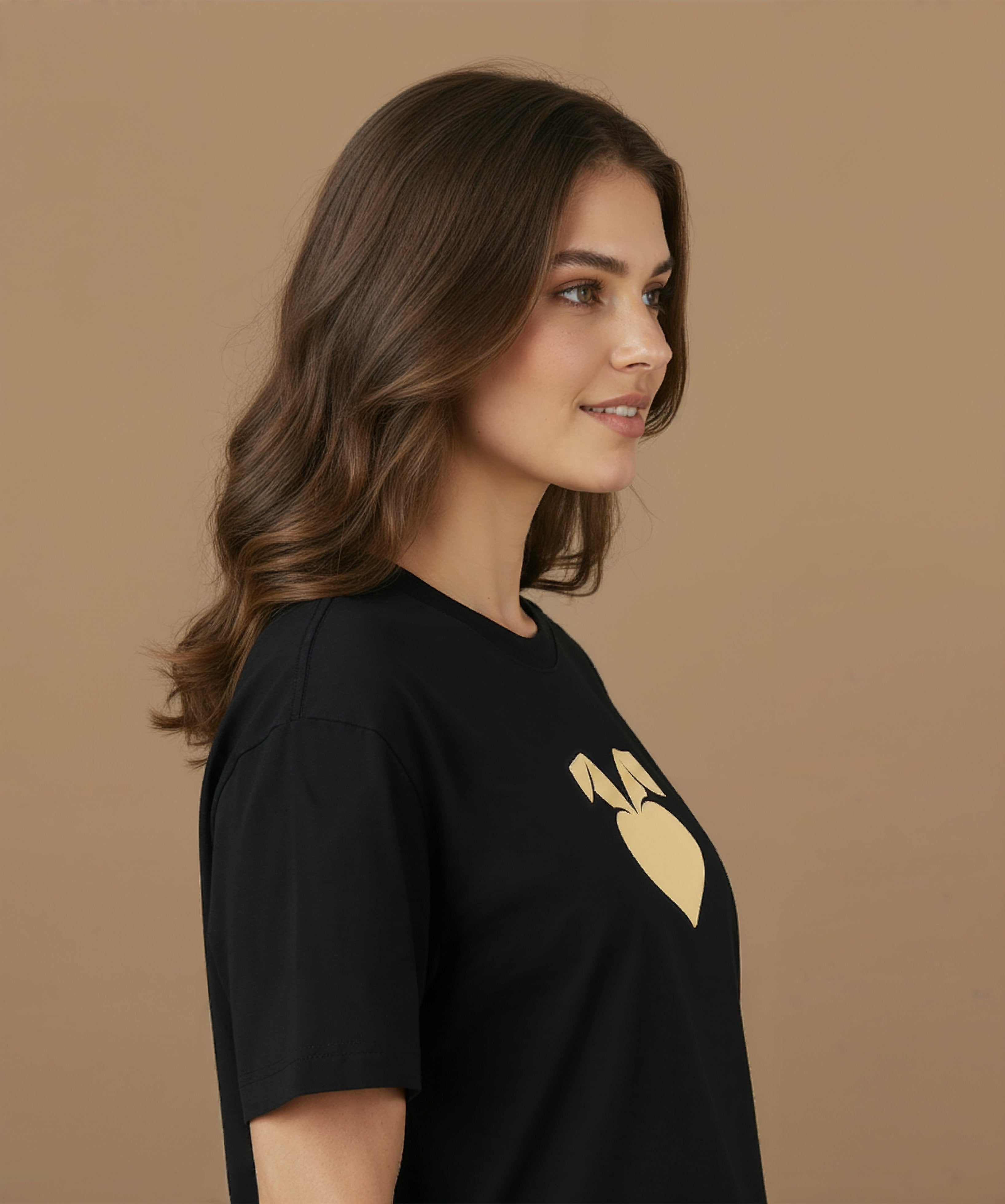a female wearing a black sweethearts mood edition logo t-shirt with a gold heart design on a brown background, angled right