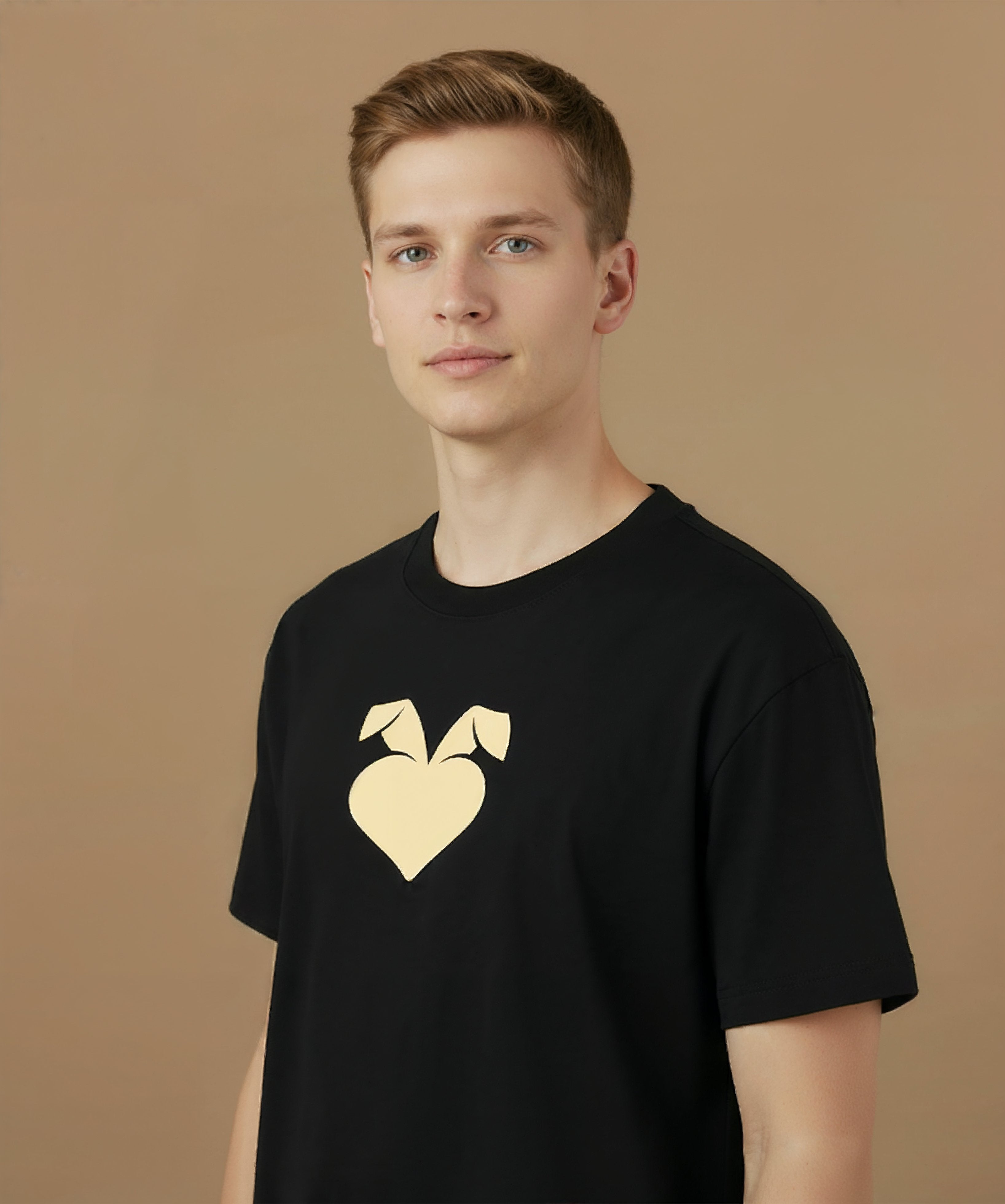 a male wearing a black sweethearts mood edition logo t-shirt with a gold heart design on a brown background, angled left