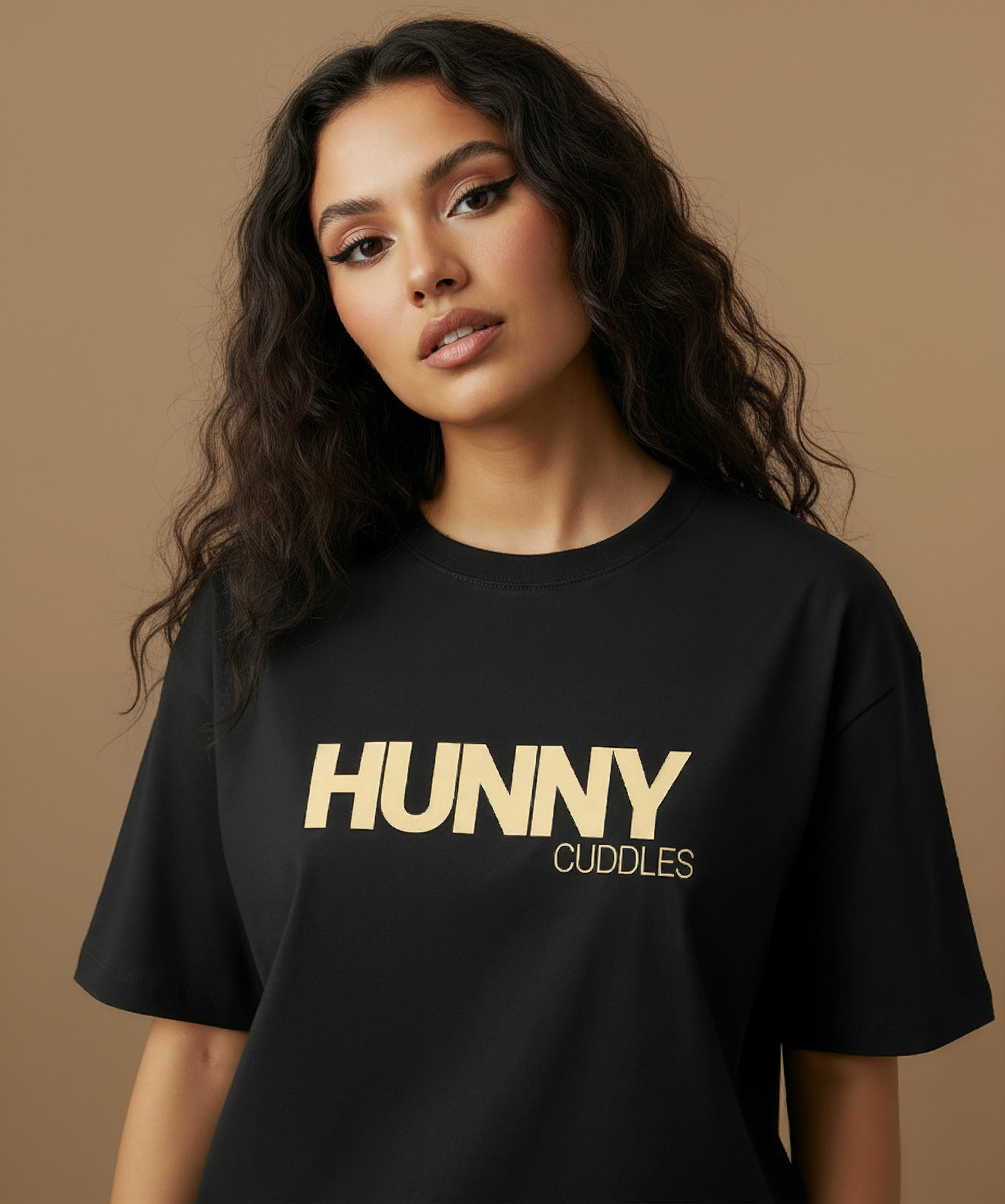 female model wearing a black t-shirt with 'HUNNY CUDDLES' text on a beige background