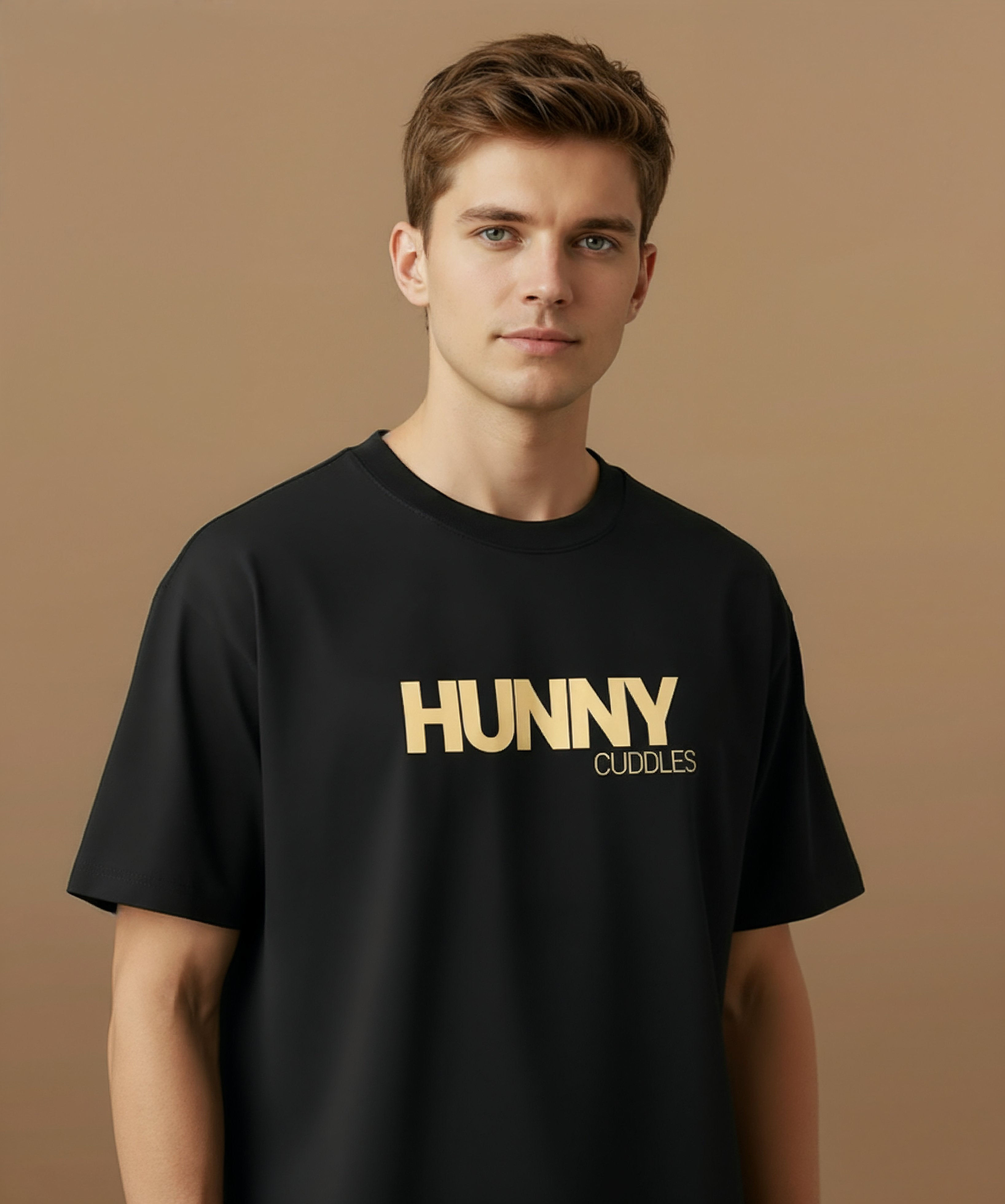 Male model wearing a black t-shirt with 'HUNNY CUDDLES' text on a beige background, angled right