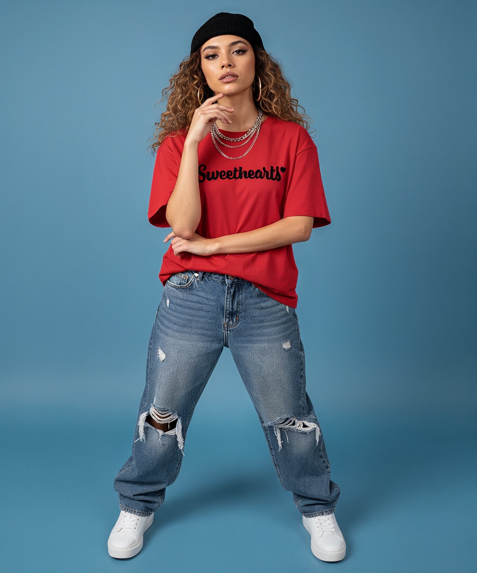 female wearing a red 'Sweetheart' shirt, blue jeans, and white sneakers on a blue background, front view