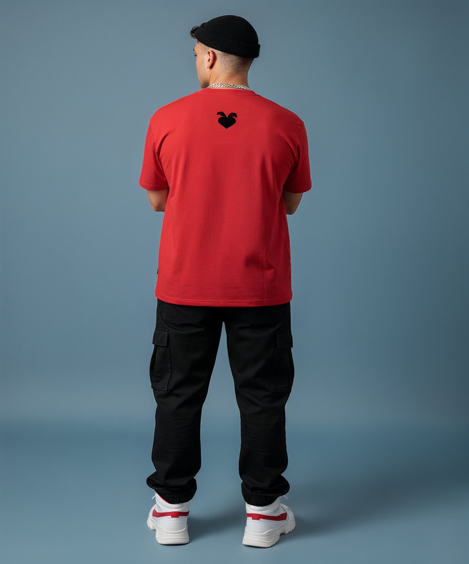 male wearing a red 'Sweetheart' shirt, blue jeans, and white sneakers on a blue background, back view