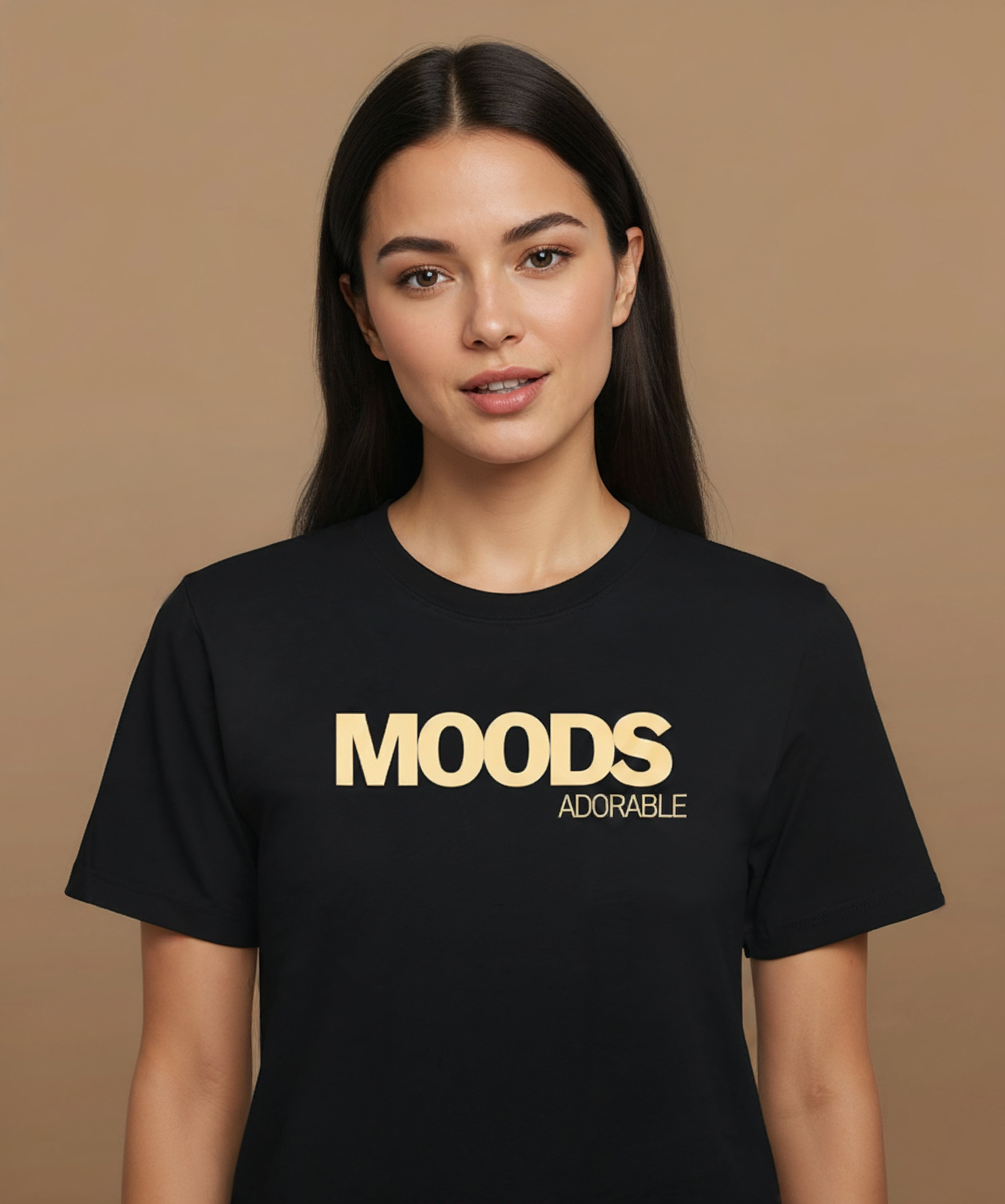 A female wearing a black t-shirt with 'MOODS', adorable, printed in gold on a brown background