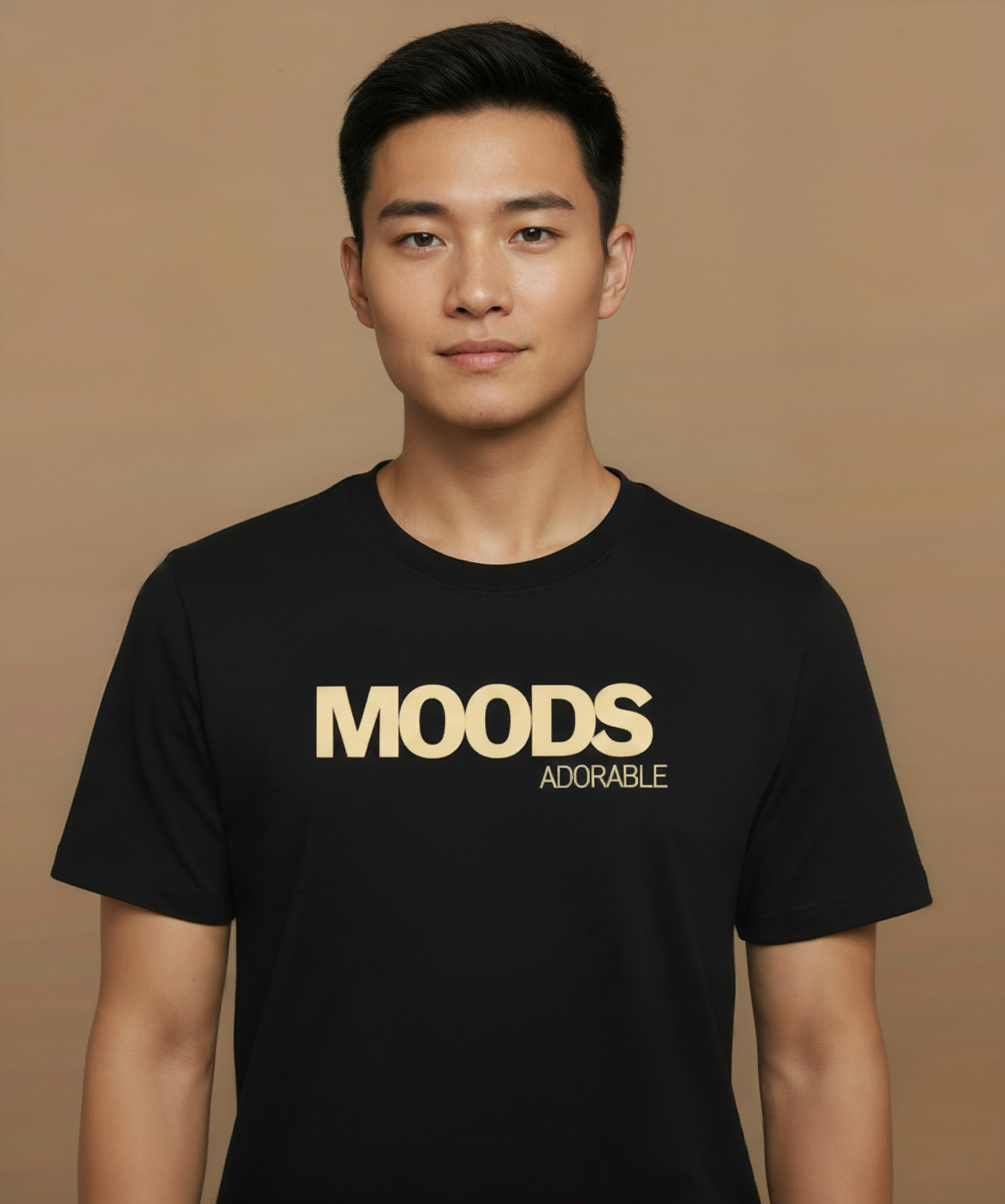 Man wearing a black t-shirt with 'MOODS', adorable, printed in gold on a brown background