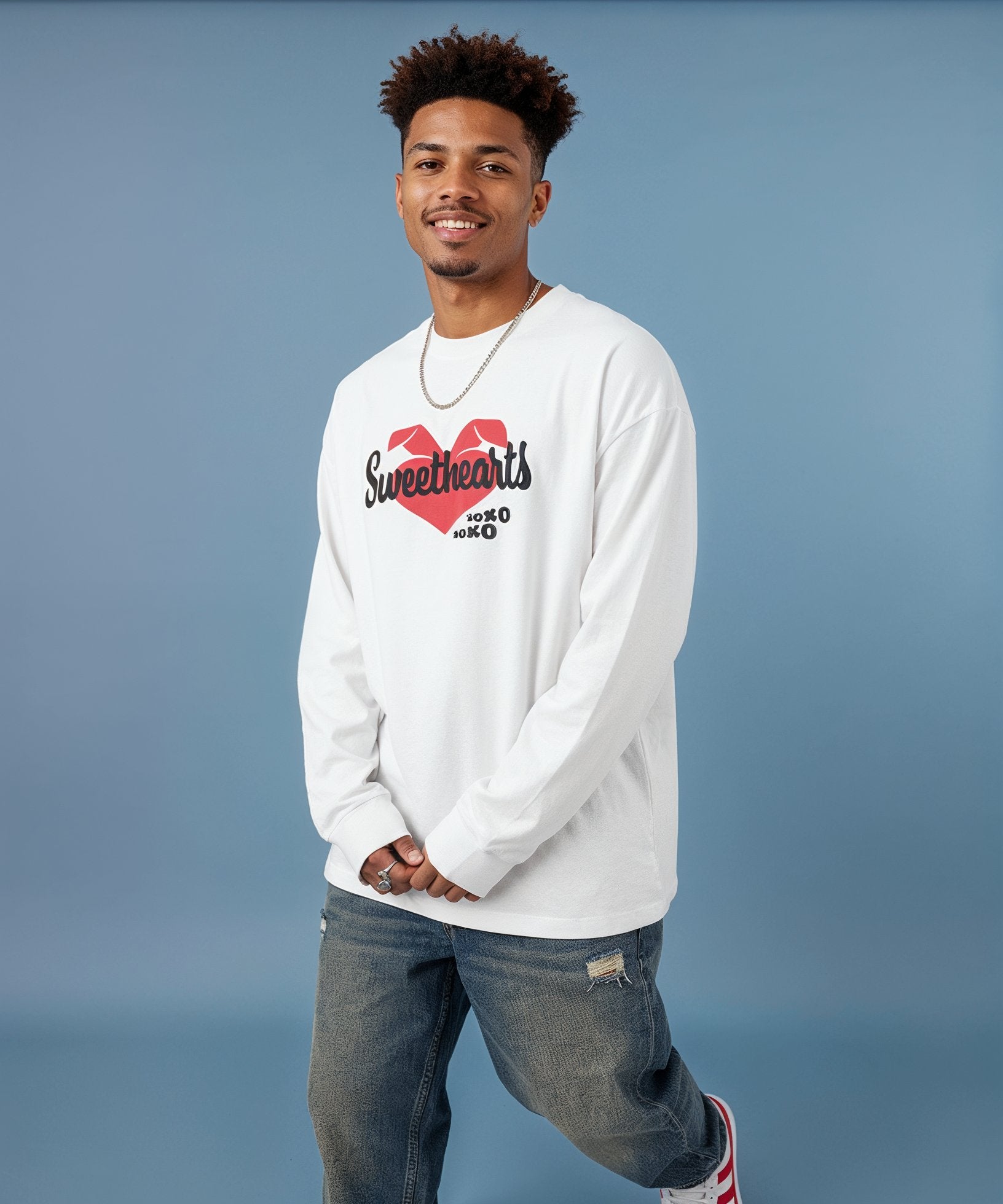 Man wearing a sweethearts white long-sleeve shirt with a red heart design on a blue background