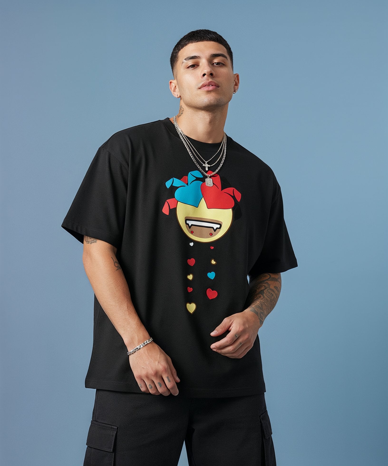 Man wearing a black t-shirt with a colorful sweethearts emoji design on a blue background