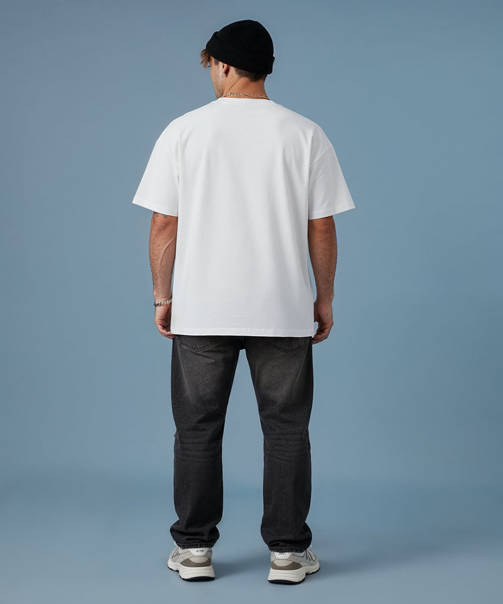 male wearing a sweethearts white t-shirt with a colorful graphic design and ripped jeans on a blue background. back view