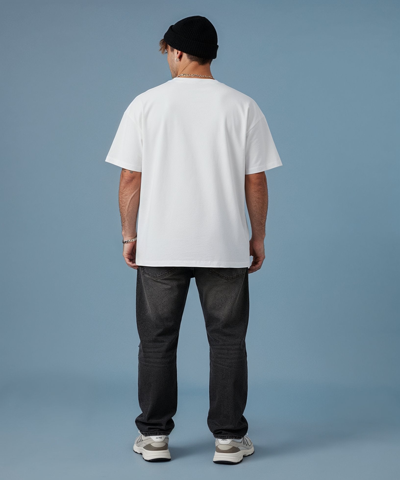 male wearing a sweethearts white t-shirt with a colorful graphic design and ripped jeans on a blue background. back view