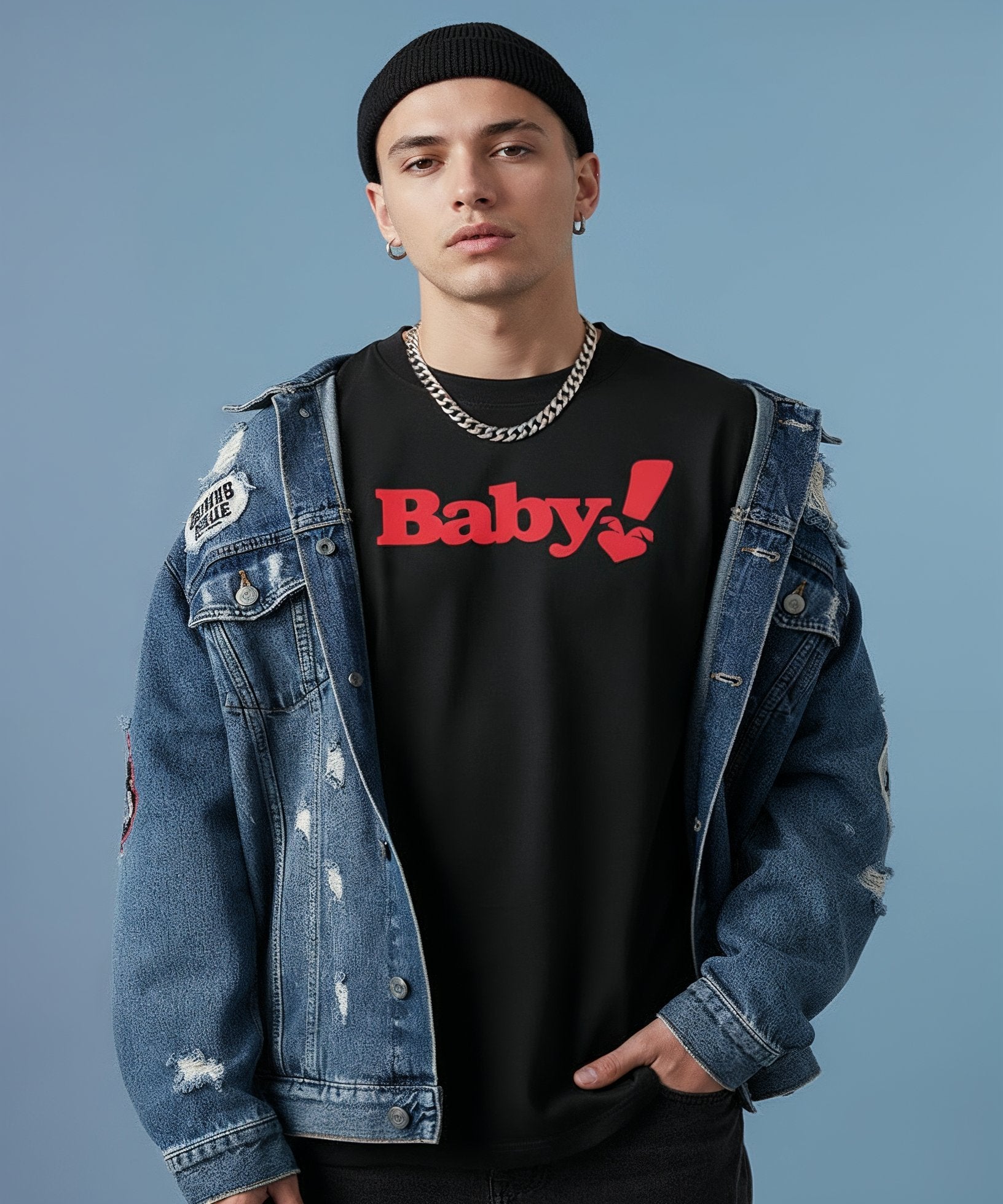 male wearing a denim jacket with patches and a black shirt with sweethearts red "baby" text, standing against a plain background. front view