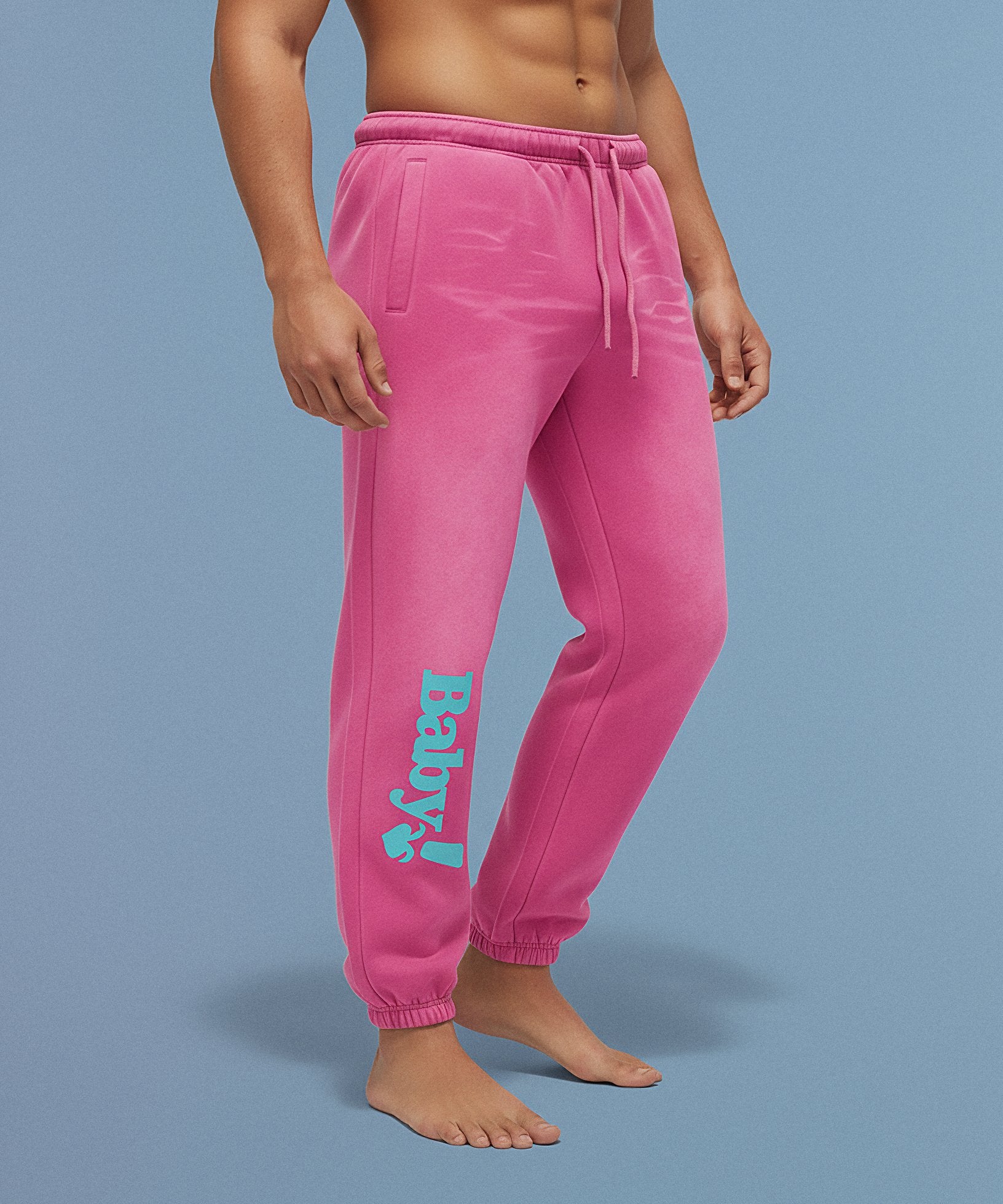 Pink sweatpants with sweethearts  'Baby!' text on a blue background, male side view