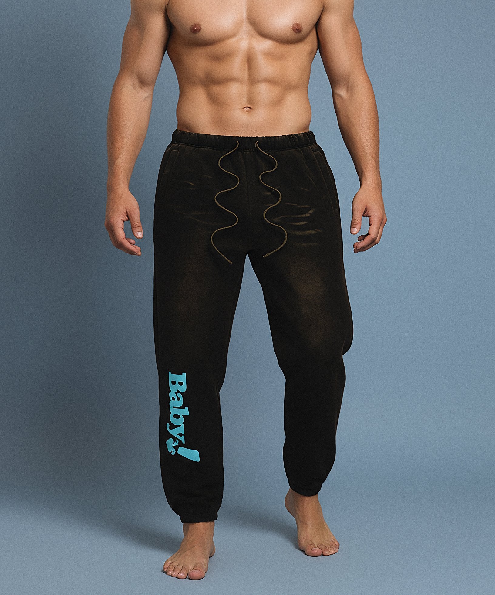 Black sweatpants with sweethearts 'Baby!' text on a gray background, male front view