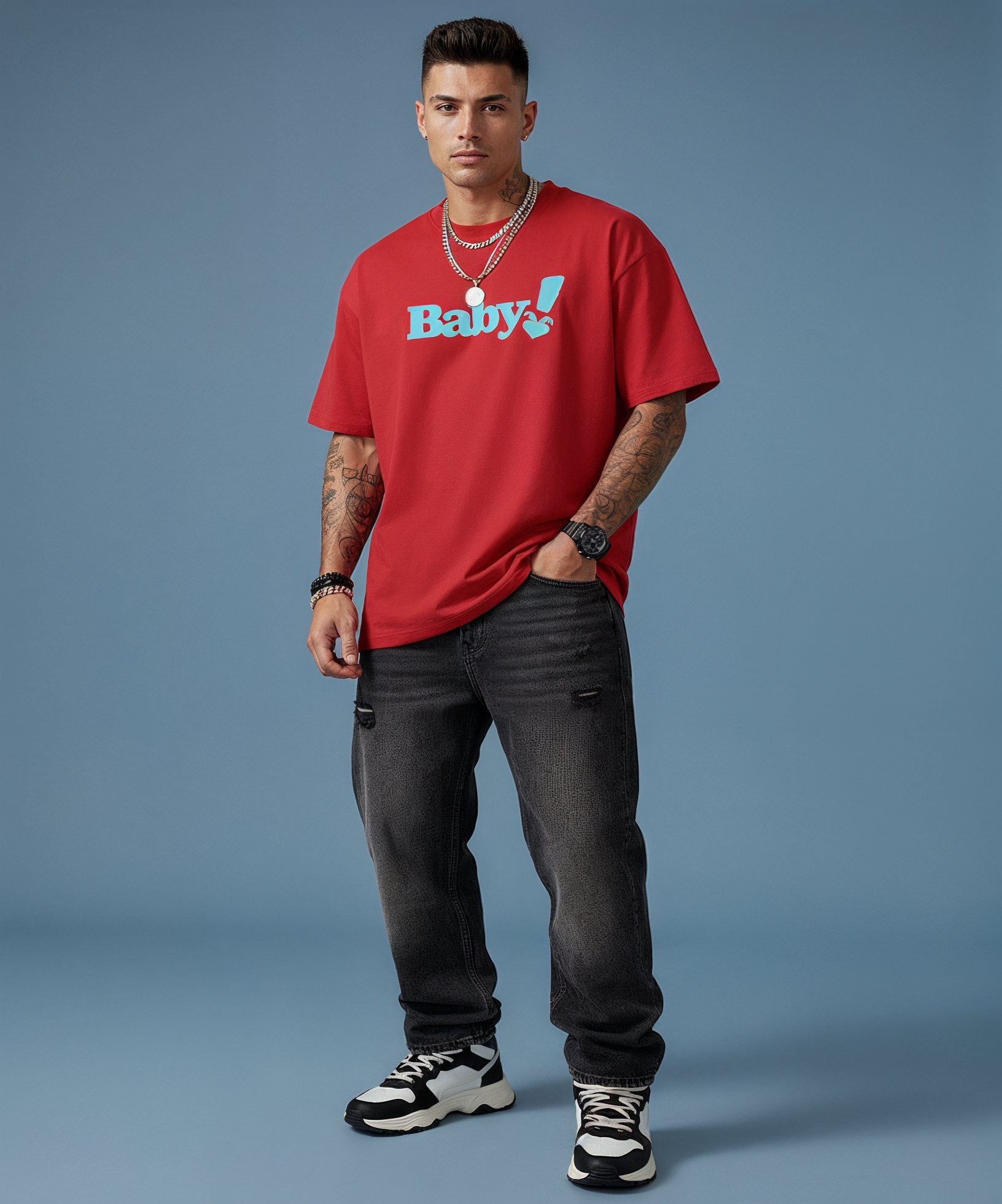 Man wearing a red t-shirt with 'Baby!' text, black jeans, and black and white sneakers on a blue background
