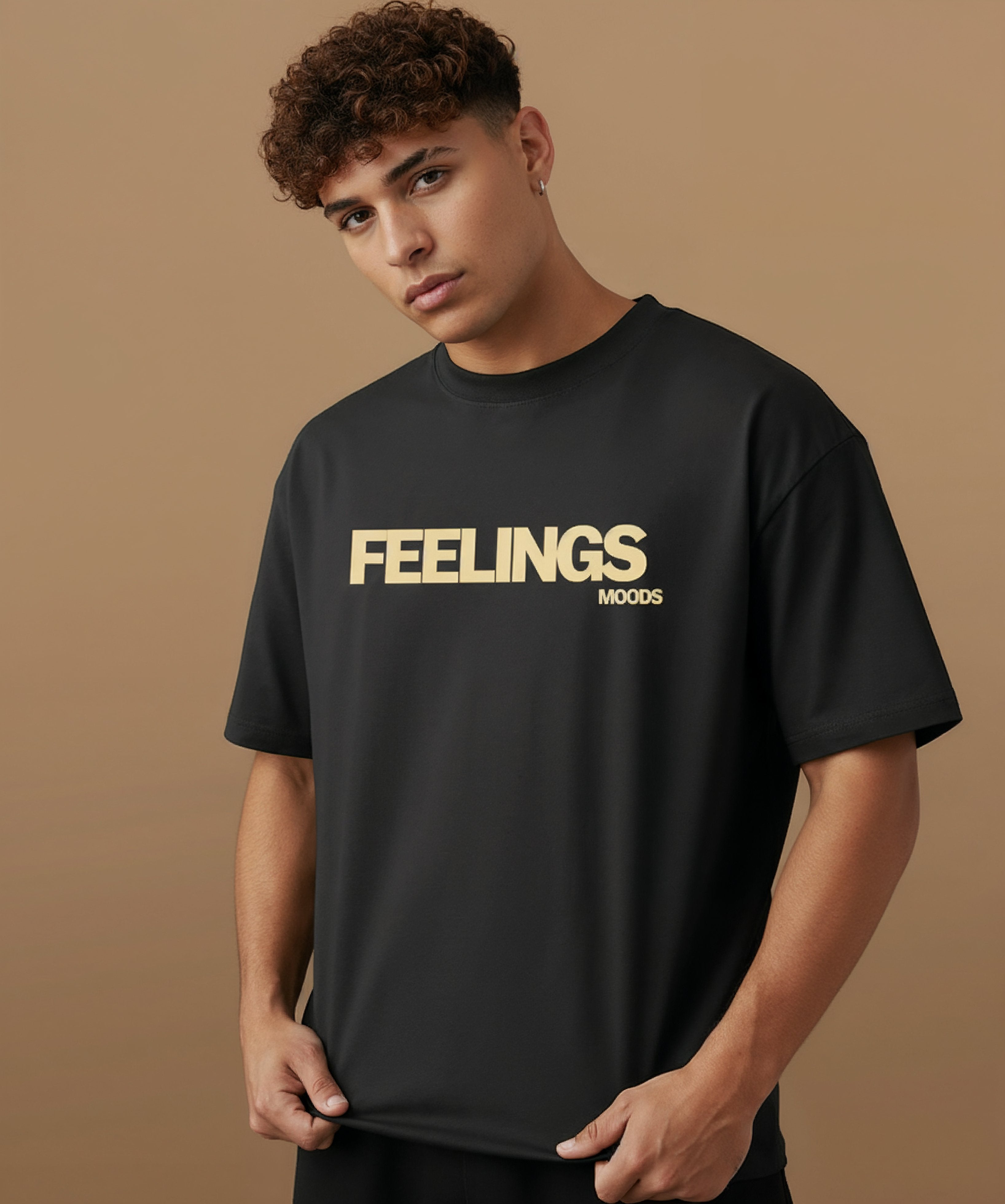 male model wearing a black t-shirt with  sweethearts brand 'FEELINGS MOODS' text on a brown background. angled left