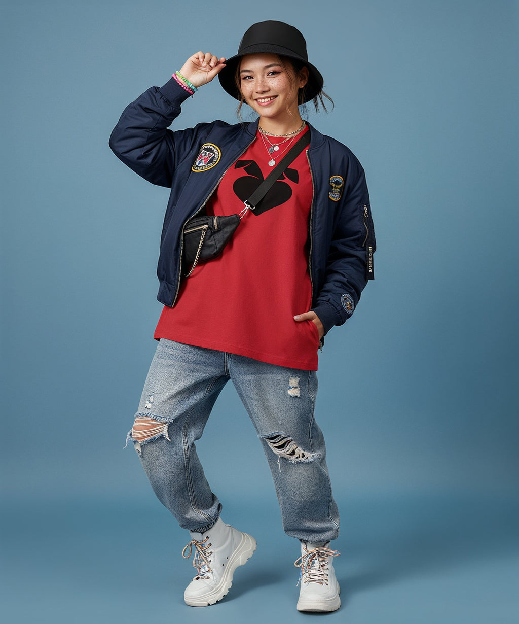 female wearing a red shirt sweethearts logo, blue jacket, and jeans with a black hat on a blue background