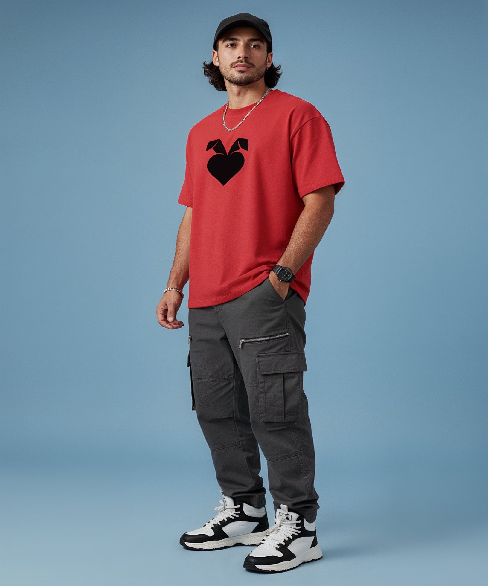 Man wearing a red t-shirt with a sweethearts logo, gray cargo pants, and black and white sneakers on a blue background