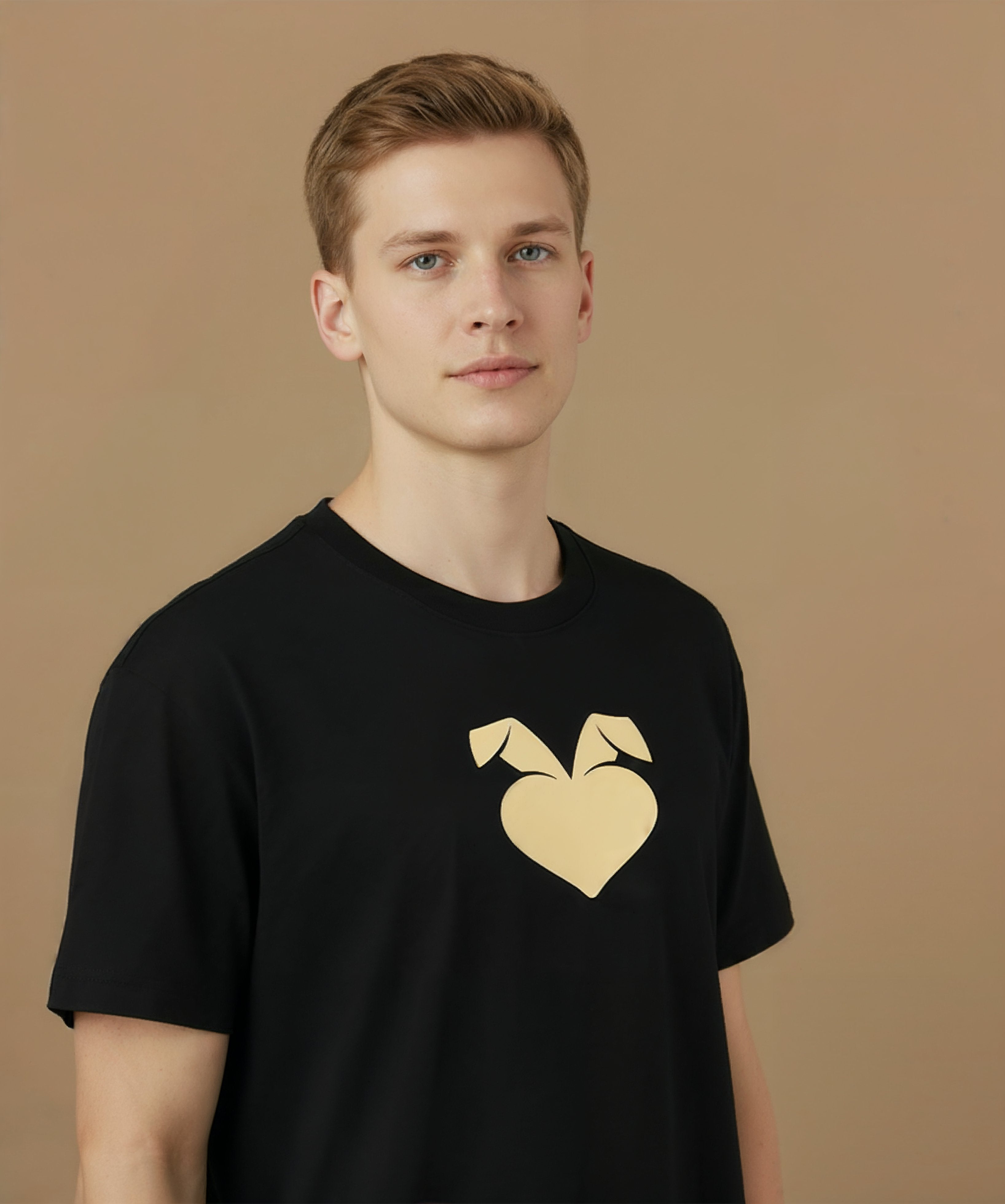 a male wearing a black sweethearts mood edition logo t-shirt with a gold heart design on a brown background, angled right