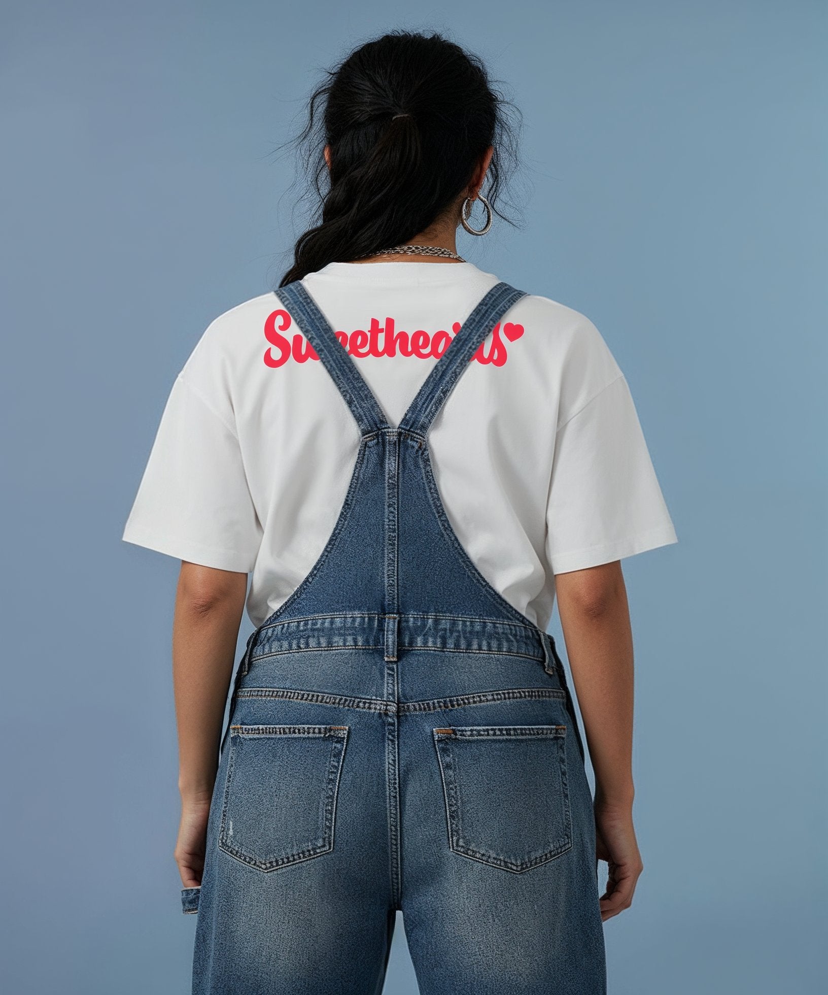 female model wearing white t-shirt with a red sweethearts logo text design on a blue background, back view