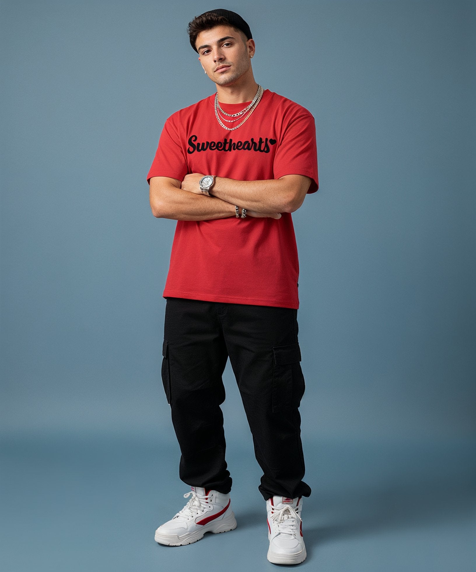 male wearing a red 'Sweetheart' shirt, blue jeans, and white sneakers on a blue background, front view