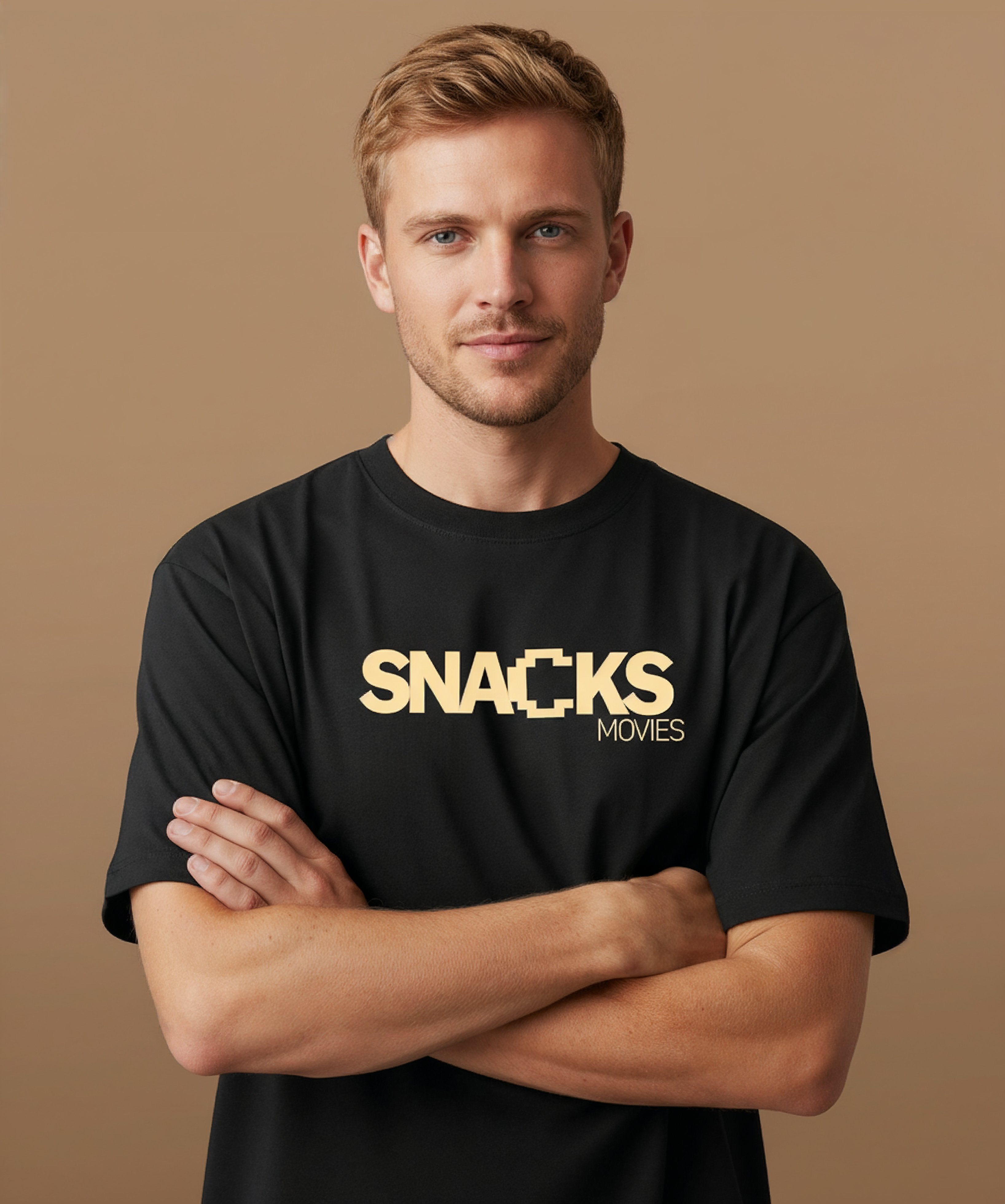 Male model wearing a black t-shirt with sweethearts brand 'SNACKS' printed in yellow from moods collection on a brown background. centered front