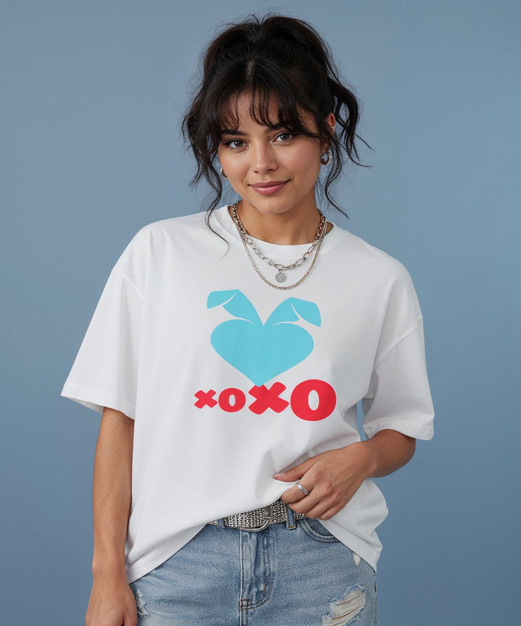 female wearing a white t-shirt with the sweethearts hearts and hugs logo  graphic design on a gray background