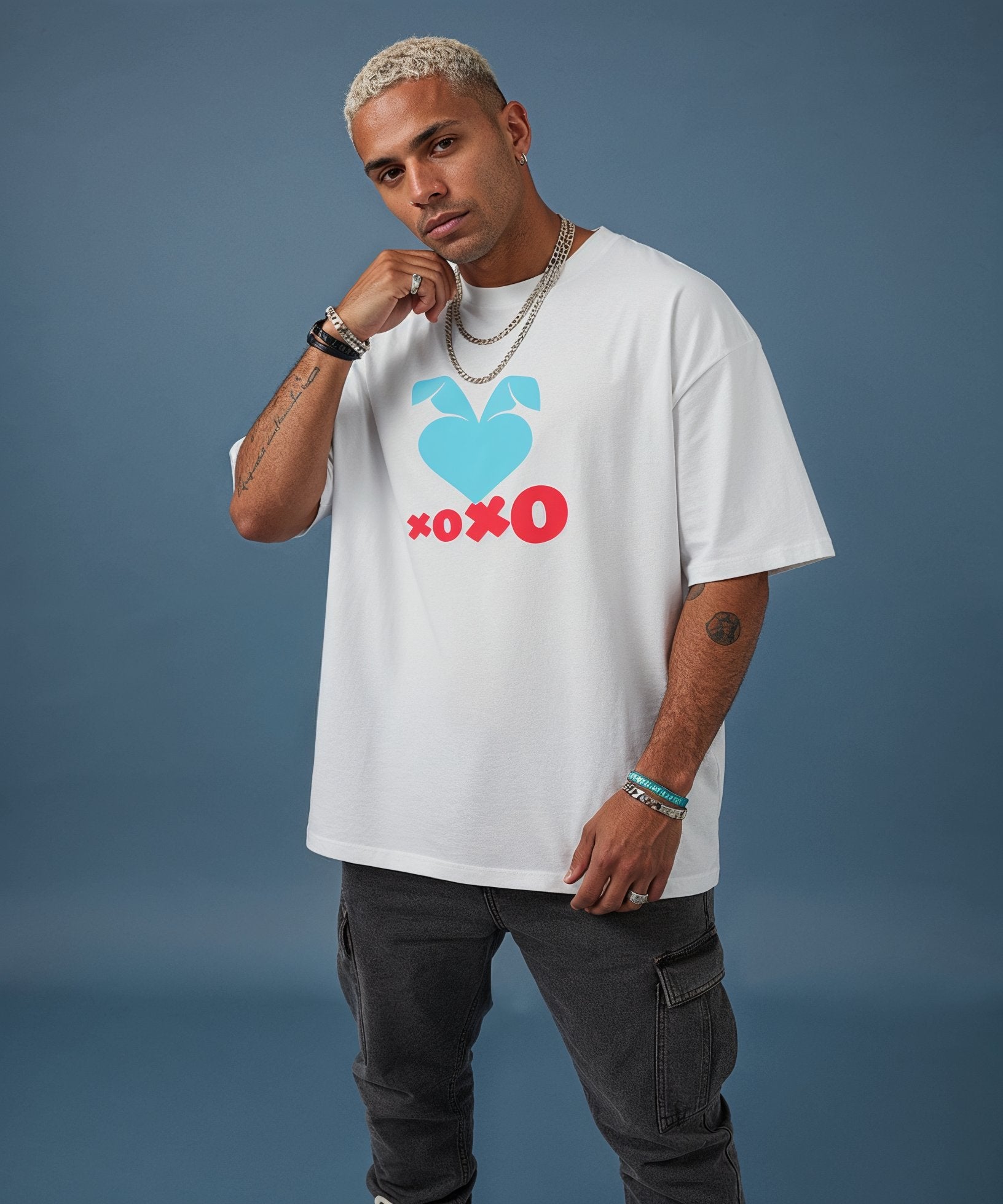 male wearing a white t-shirt with the sweethearts hearts and hugs logo  graphic design on a gray background