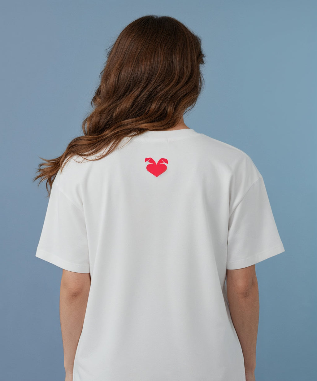 female wearing a white t-shirt with a sweethearts red heart logo design on the back against a blue background