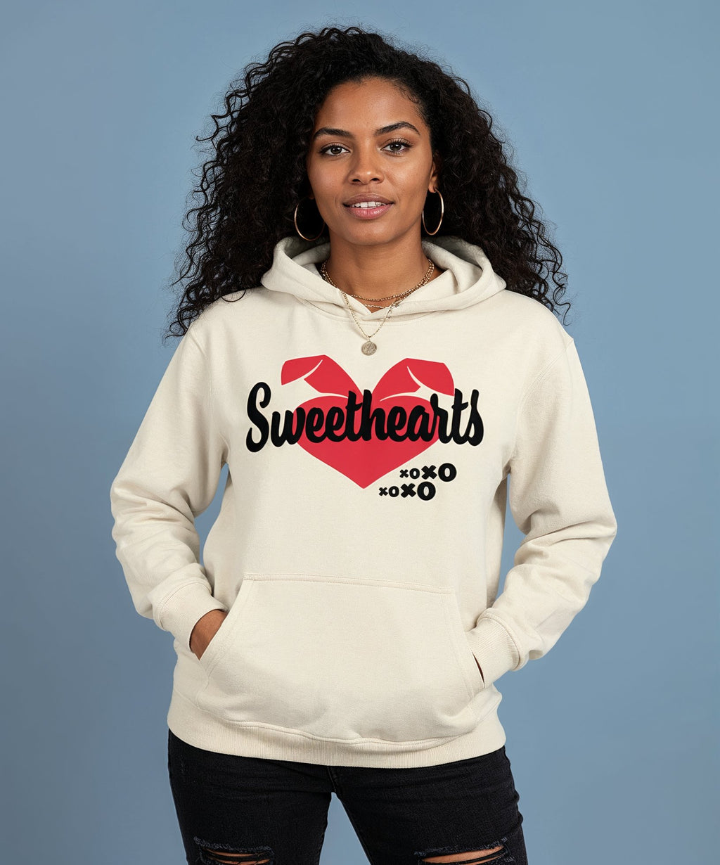 Woman wearing a cream hoodie with 'Sweethearts' design on a blue background