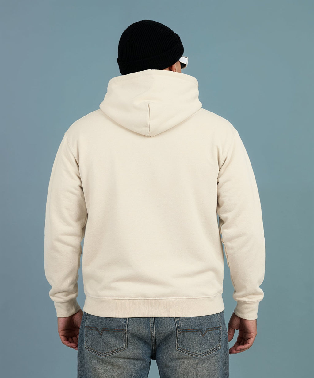 Person wearing a cream hoodie and black beanie on a plain background