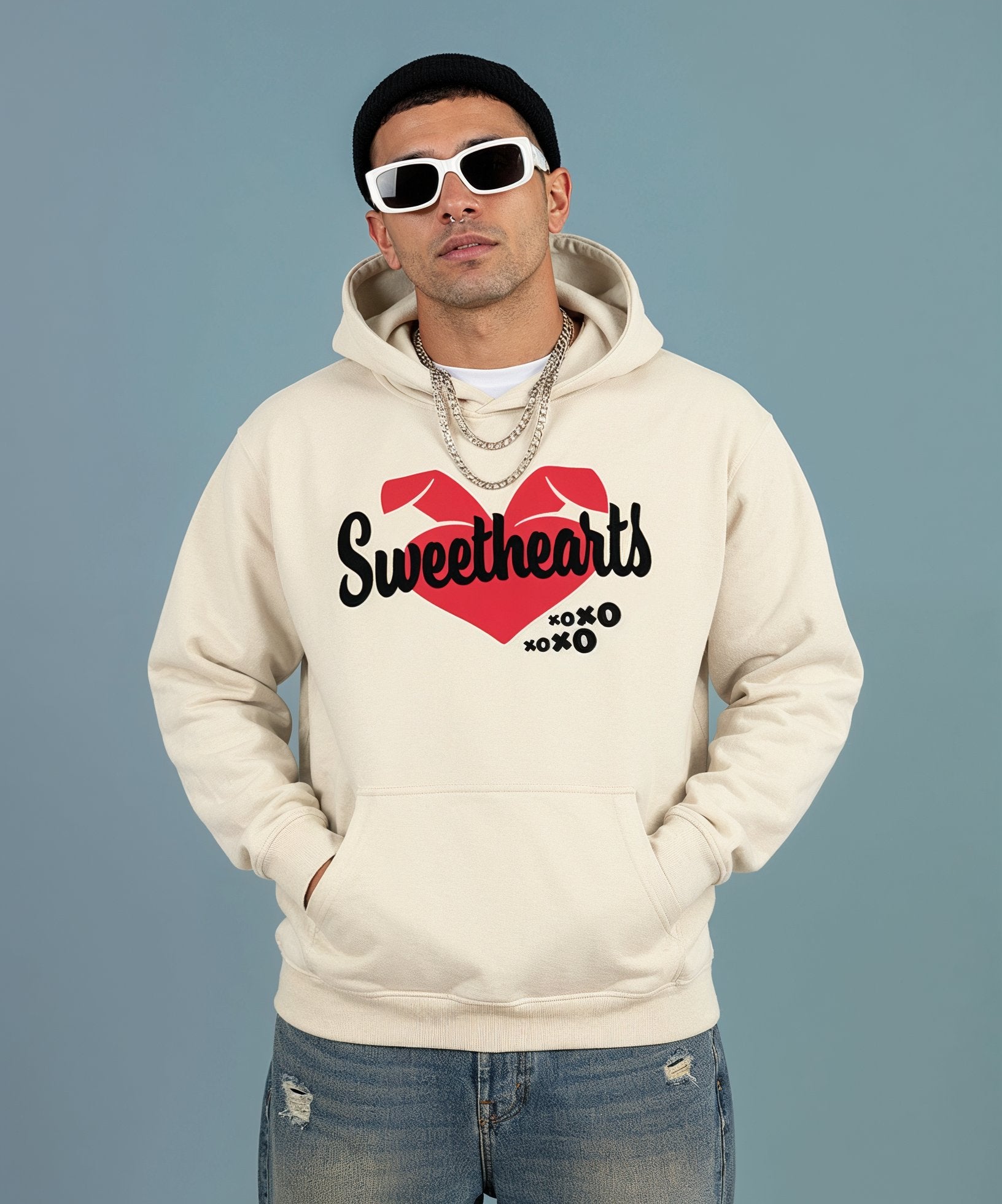 Man wearing a beige hoodie with 'Sweethearts' design on a blue background